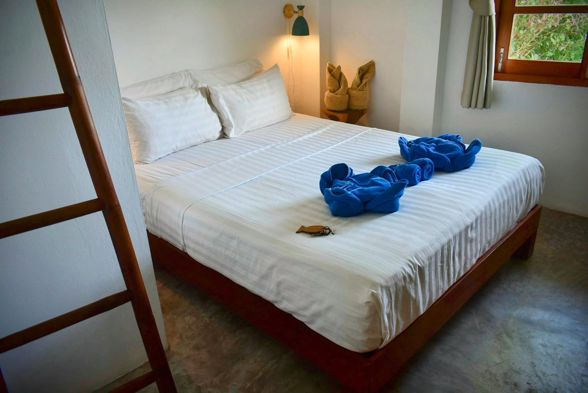 Double bedroom with white linens and towel art at The Trevally House