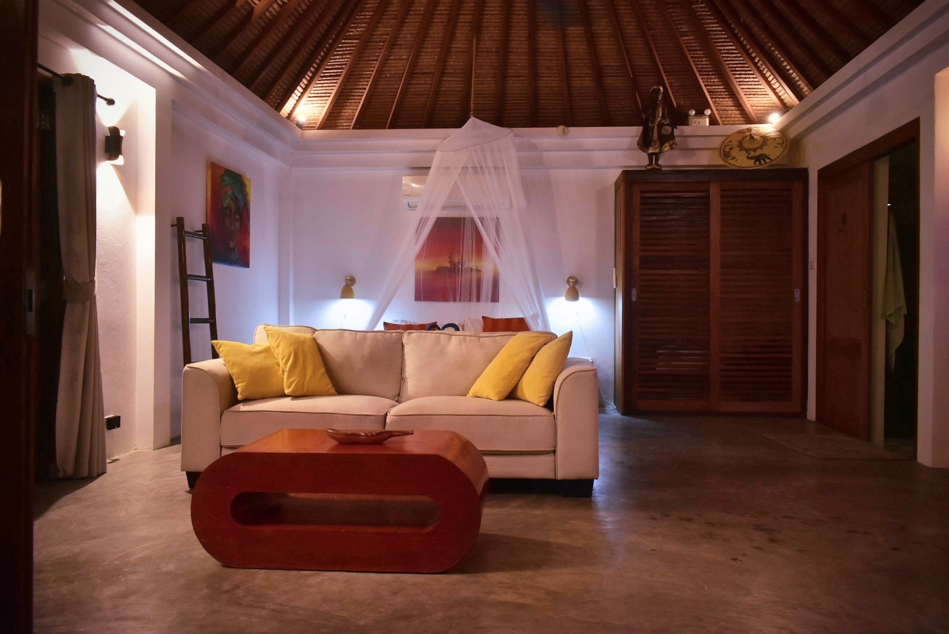 Living area with sofa and canopy bed under the vaulted roof in the evening at The Trevally House