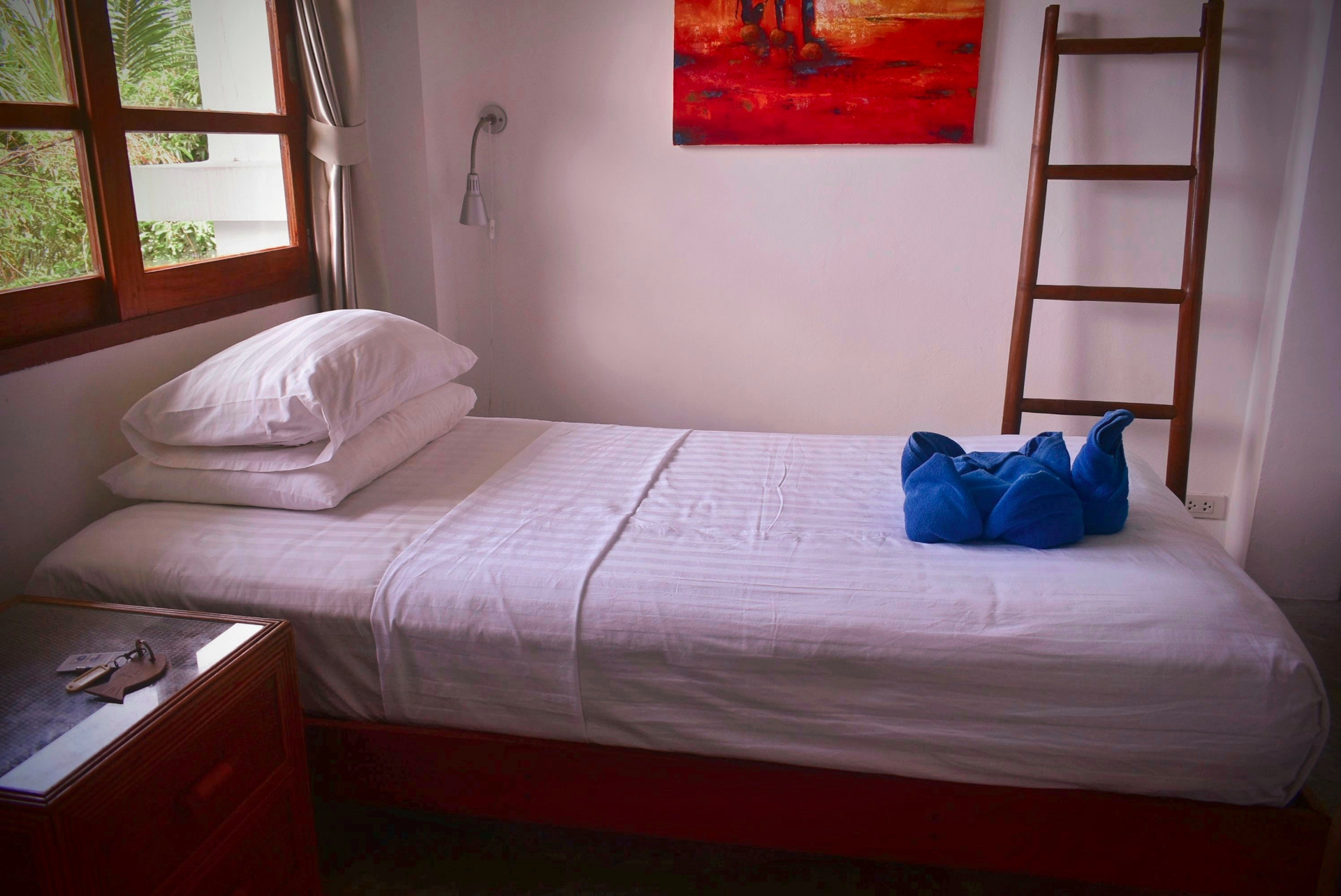 Single bedroom with red artwork and garden view at The Trevally House